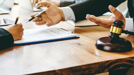 Zweo Personen sitzen an einem Schreibtisch gegenüber. Sie besprechen ein Dokument. Foto: iStock.com / undefined_undefined