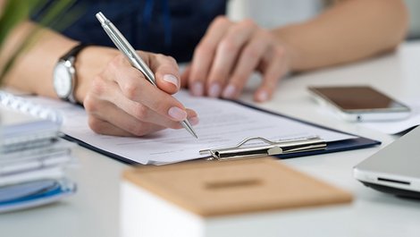 Mieterselbstauskunft, Selbstauskunft, Hände mit Stift füllen einen Zettel auf einem Klemmbrett aus, Foto: iStock.com / Dutko