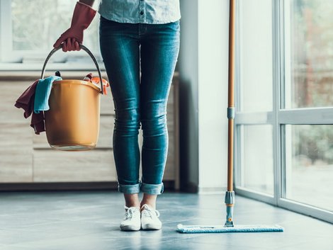 Wohnungsschlüssel, Frau mit Reinigungshandschuhen hält Wischeimer und Bodenwischer in den Händen, Foto: VadimGuzhva/stock.adobe.com