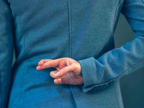 Hinter dem Rücken gekreuzte Finger