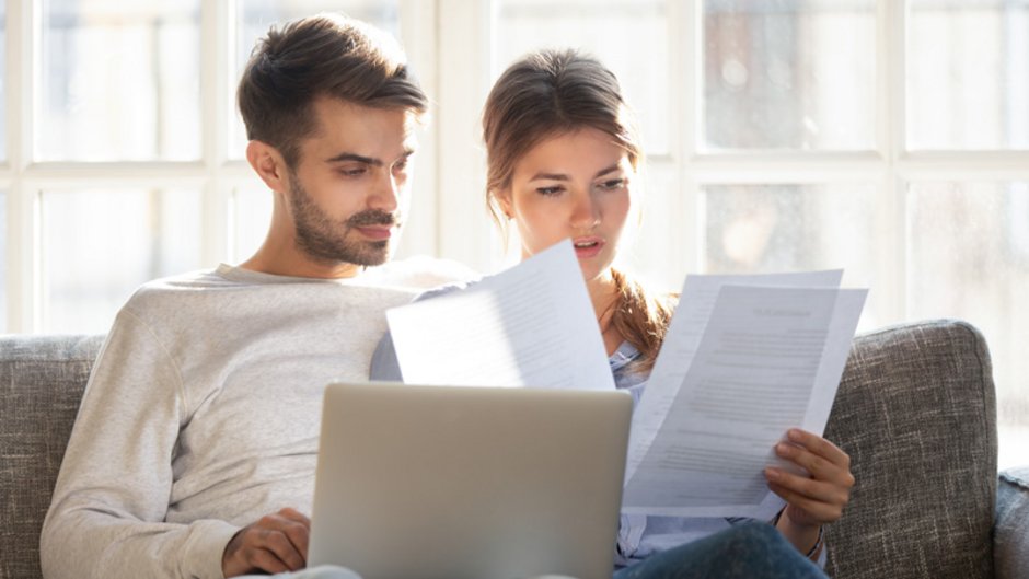 Restschuldversicherung, Paar prüft auf den Sofa sitzend einen Vertrag, Foto: fizkes / stock.adobe.com
