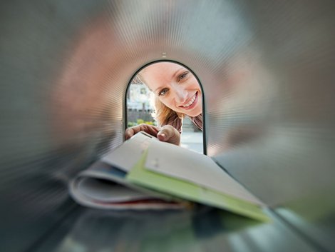 Eine Frau greift nach Briefen in einem Briefkasten