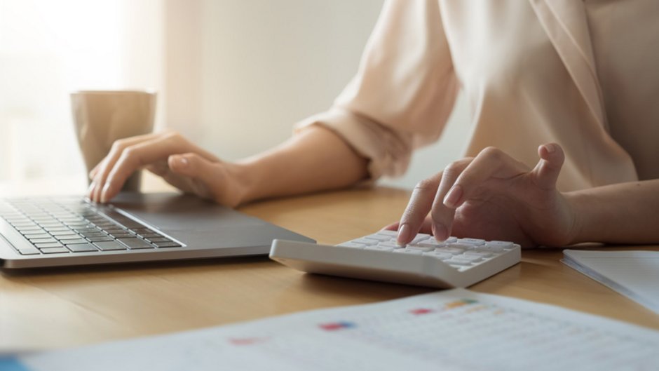 Maximale Darlehenshöhe, Frau sitzt vor Laptop und Taschenrechner, Foto: Natee Meepian / stock.adobe.com