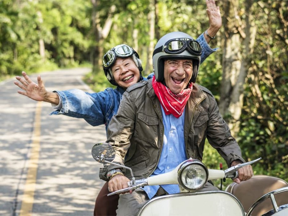 Auswandern nach Thailand, zwei lachende Rentner auf einem Motorroller fahren eine Straße entlang, Foto: Rawpixel.com/stock.adobe.com