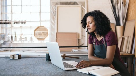Maximale Darlehenshöhe, Freiberuflerin sitzt in ihrer Werkstatt vor einem Laptop, Foto: mavoimages / stock.adobe.com