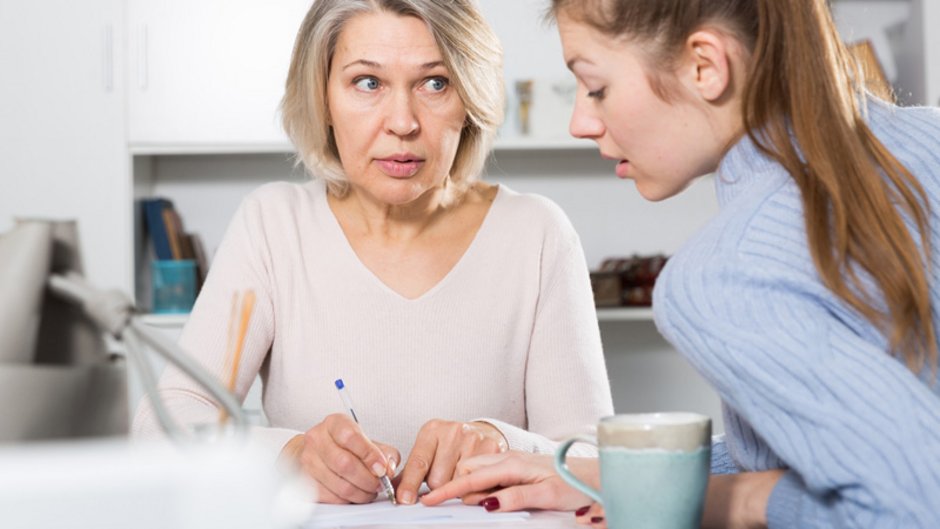 Mietbürgschaft, ältere Frau unterschreibt ein Dokument an einer Stelle, die von einer jungen Frau gezeigt wird, Foto: JackF / stock.adobe.com