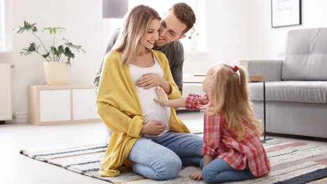 Mietaufhebungsvertrag, Schwangere sitzt mit Vater und Tochter in der Wohnung auf dem Boden , Foto: New Africa / stock.adobe.com