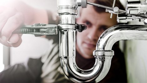 Fallen im Mietvertrag, Mann schraubt Siphon von einer Spüle ab, Foto: iStock.com / lovro77